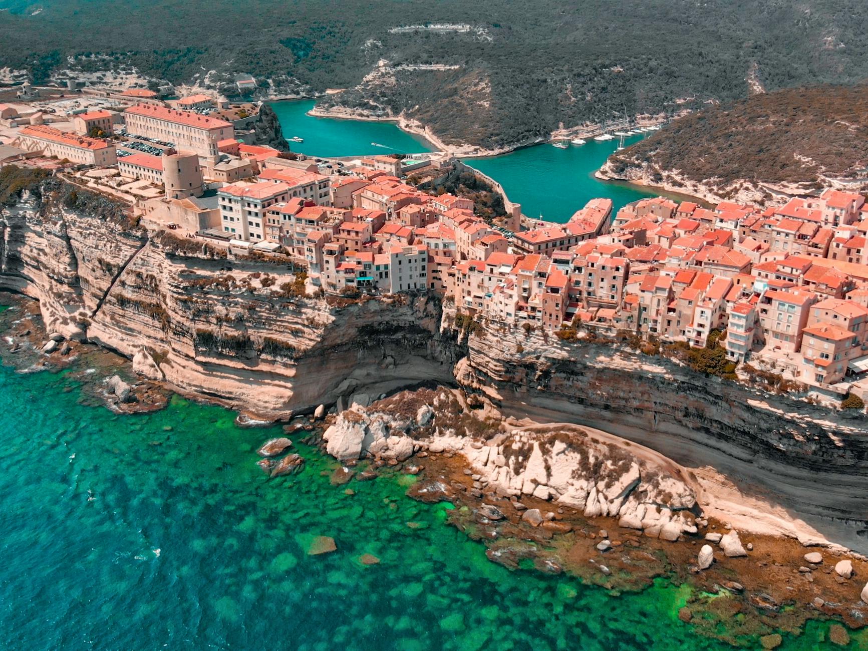 an aerial photography of houses between the ocean and mountains